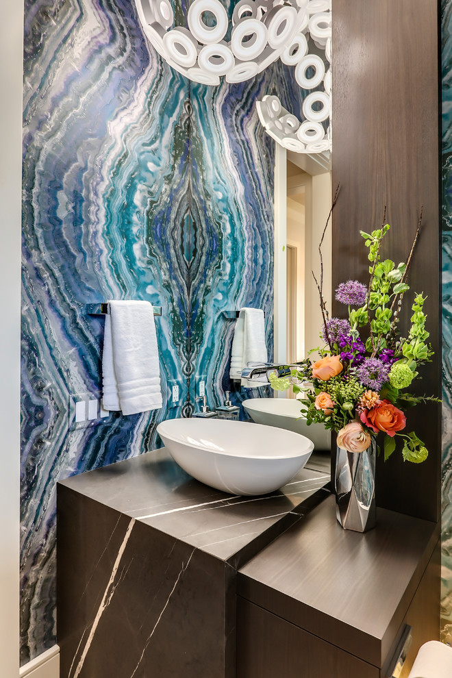 Moderne Gästetoilette mit flächenbündigen Schrankfronten, dunklen Holzschränken, blauer Wandfarbe, Aufsatzwaschbecken und schwarzer Waschtischplatte in Calgary