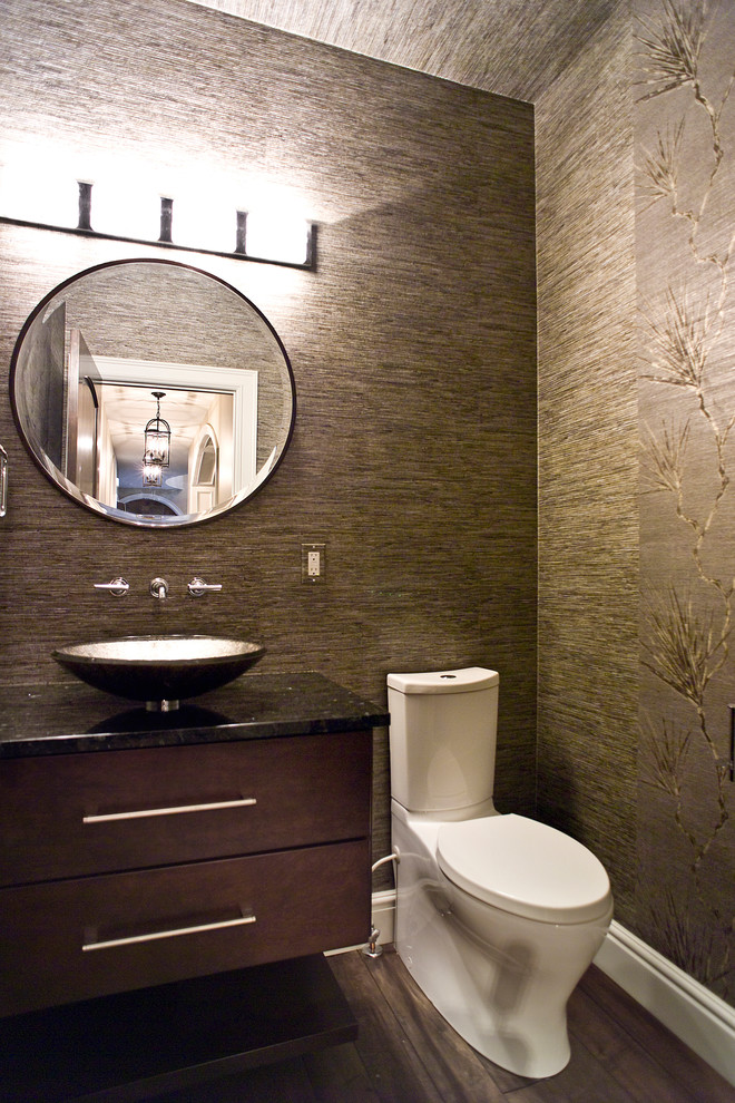 Cette photo montre un WC et toilettes tendance en bois foncé de taille moyenne avec un placard à porte plane, WC séparés, un mur multicolore, un sol en bois brun, une vasque, un plan de toilette en granite et un sol marron.