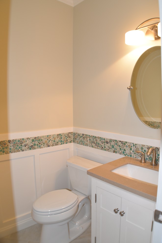 Inspiration pour un petit WC et toilettes craftsman avec un lavabo encastré, des portes de placard blanches, un plan de toilette en surface solide, WC séparés, un carrelage multicolore, un mur beige et un sol en carrelage de porcelaine.