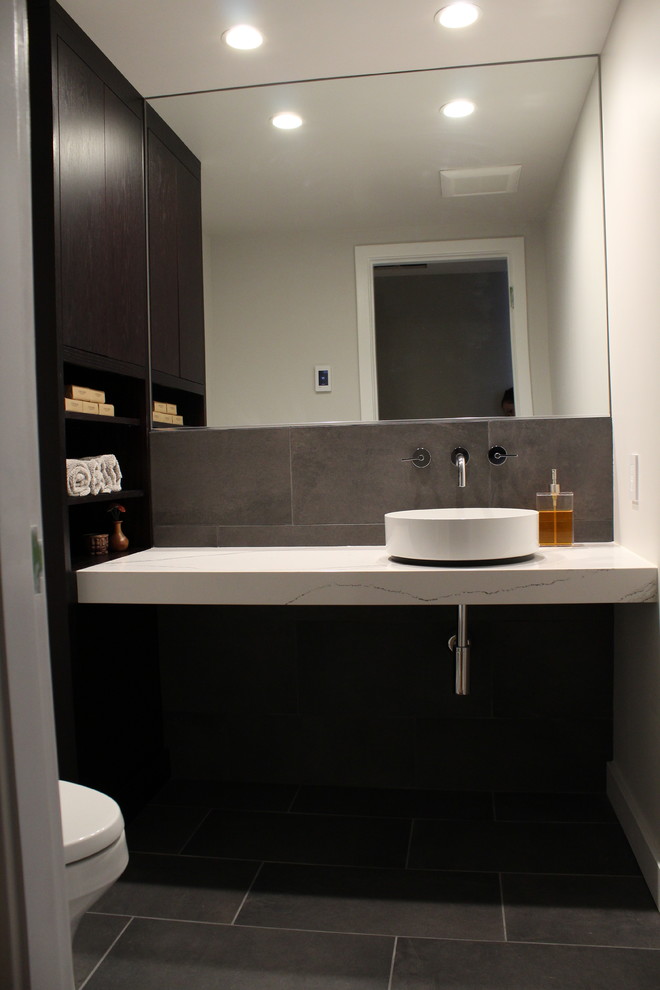 Inspiration for a medium sized modern cloakroom in Seattle with flat-panel cabinets, dark wood cabinets, a one-piece toilet, grey tiles, ceramic tiles, white walls, cement flooring, a vessel sink, engineered stone worktops, grey floors and white worktops.