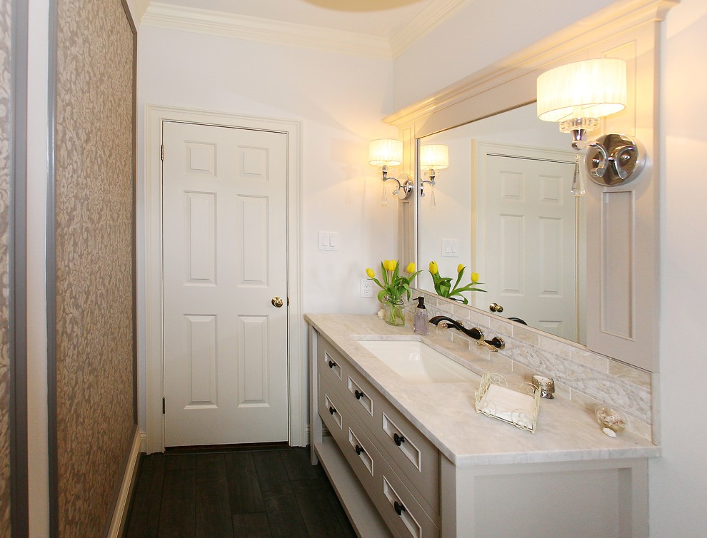Foto på ett stort vintage vit toalett, med möbel-liknande, vita skåp, en toalettstol med separat cisternkåpa, beige väggar, plywoodgolv, ett undermonterad handfat och marmorbänkskiva