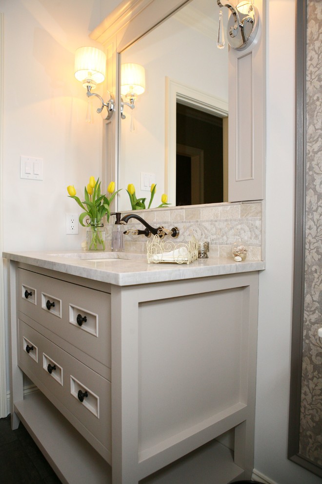 Inredning av ett klassiskt stort toalett, med möbel-liknande, vita skåp, en toalettstol med separat cisternkåpa, beige väggar, plywoodgolv, ett undermonterad handfat och marmorbänkskiva