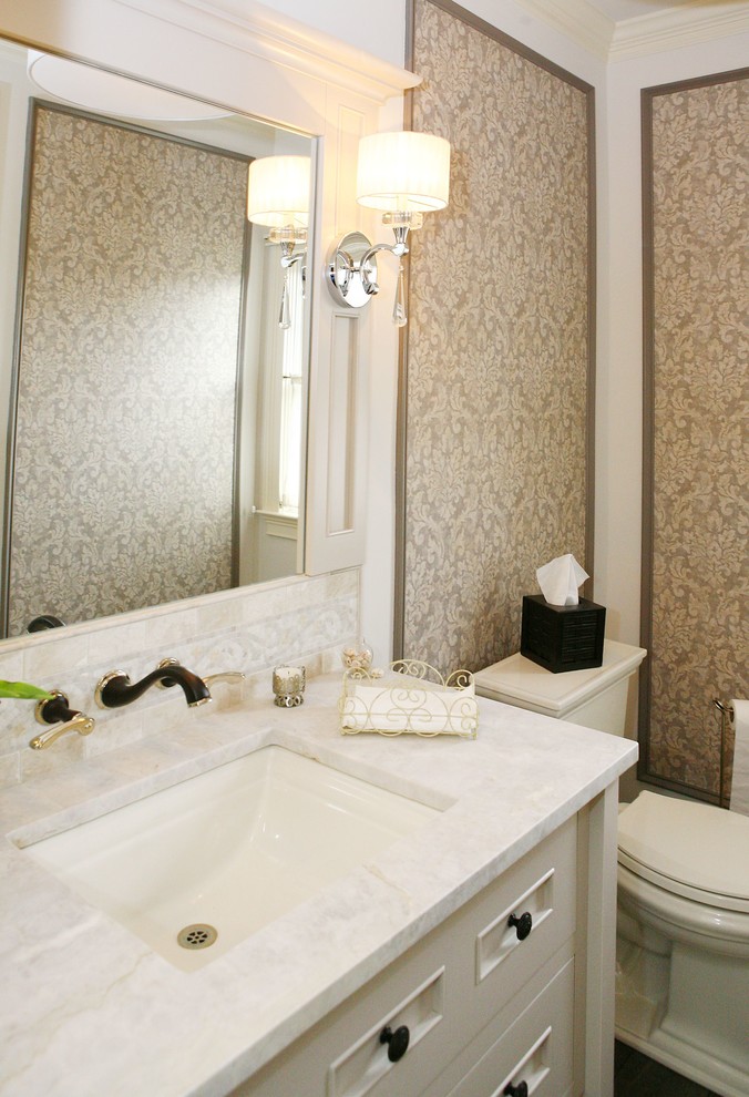 Mid-sized transitional plywood floor powder room photo in Philadelphia with furniture-like cabinets, white cabinets, a two-piece toilet, beige walls, an undermount sink, marble countertops and white countertops