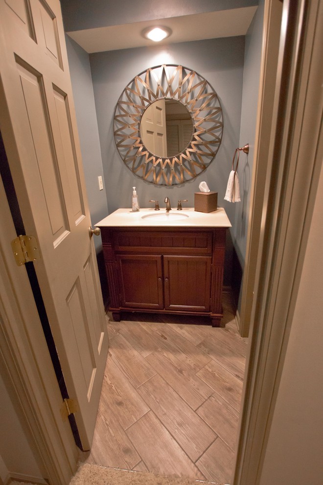Inredning av ett klassiskt litet toalett, med skåp i shakerstil, bruna skåp, blå väggar, klinkergolv i porslin, ett undermonterad handfat och brunt golv