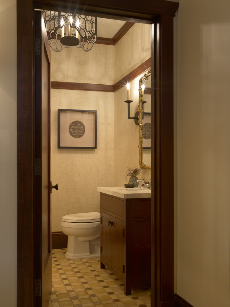 Inredning av ett klassiskt grå grått toalett, med möbel-liknande, bruna skåp, en toalettstol med separat cisternkåpa, beige väggar och brunt golv