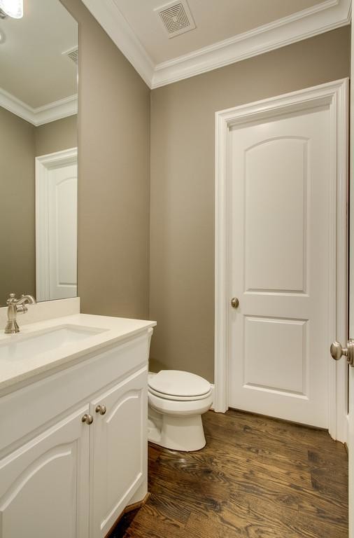 Bild på ett litet vintage toalett, med luckor med upphöjd panel, vita skåp, en toalettstol med hel cisternkåpa, beige väggar, mörkt trägolv, ett nedsänkt handfat och bänkskiva i kvartsit