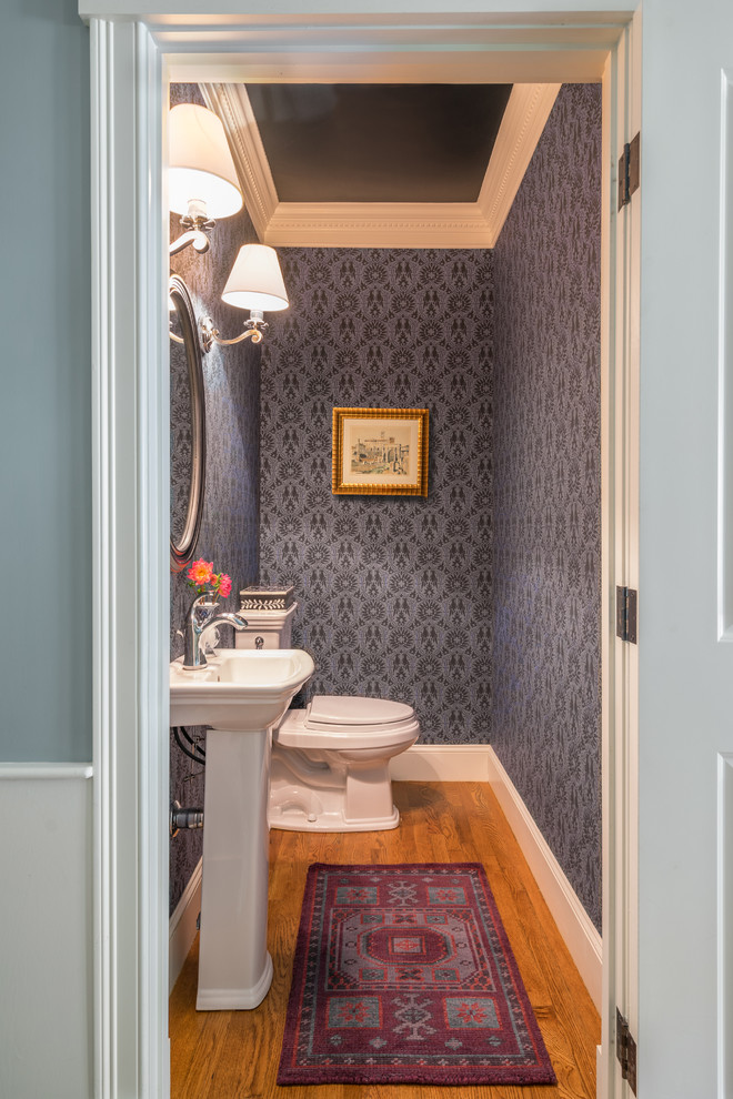Imagen de aseo tradicional renovado pequeño con paredes púrpuras, suelo de madera en tonos medios y lavabo con pedestal