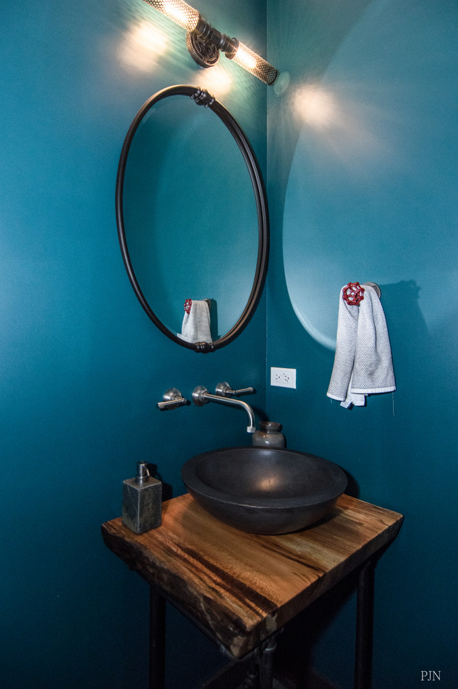 シカゴにある小さなエクレクティックスタイルのおしゃれなトイレ・洗面所 (オープンシェルフ、中間色木目調キャビネット、壁掛け式トイレ、青い壁、セラミックタイルの床、ベッセル式洗面器、木製洗面台) の写真