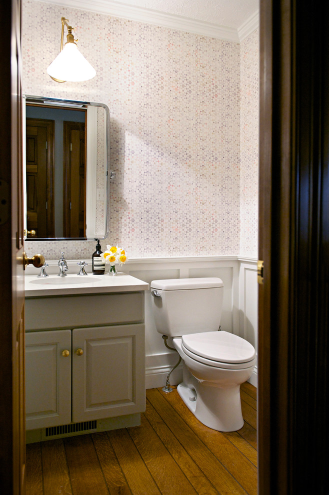 Bild på ett litet vintage toalett, med luckor med upphöjd panel, grå skåp, en toalettstol med separat cisternkåpa, vita väggar, mellanmörkt trägolv, ett undermonterad handfat, bänkskiva i kvarts och brunt golv