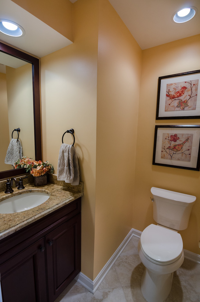 Inspiration for a small timeless beige tile porcelain tile powder room remodel in DC Metro with dark wood cabinets, granite countertops, an undermount sink, raised-panel cabinets, a two-piece toilet and yellow walls