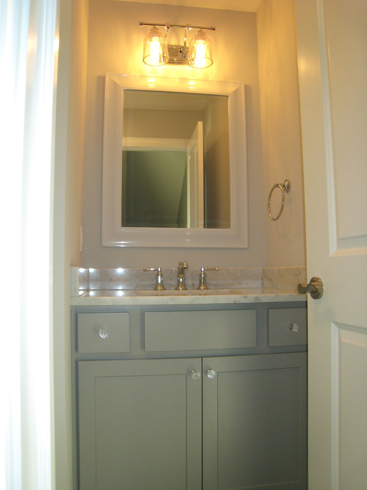 Cette image montre un WC et toilettes traditionnel avec un placard à porte shaker, des portes de placard grises et un plan de toilette en marbre.