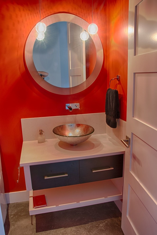 Réalisation d'un WC et toilettes minimaliste de taille moyenne avec un placard à porte plane, des portes de placard grises, WC à poser, un mur rouge, sol en béton ciré, une vasque et un plan de toilette en granite.
