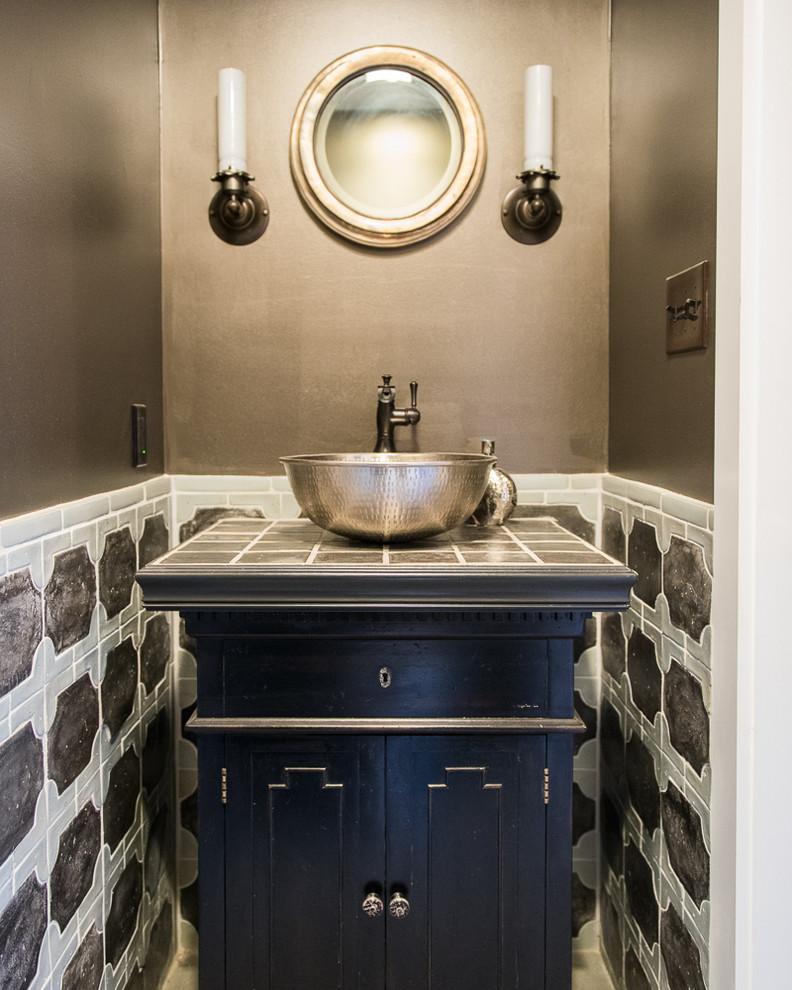 Modelo de aseo tradicional con lavabo sobreencimera, armarios tipo mueble, puertas de armario negras, encimera de azulejos, baldosas y/o azulejos multicolor y encimeras grises