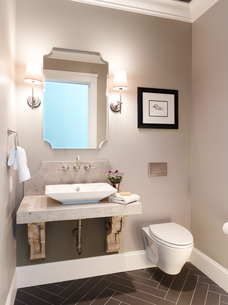 Inredning av ett klassiskt toalett, med ett fristående handfat, bänkskiva i kalksten, en vägghängd toalettstol, grå kakel, grå väggar och klinkergolv i porslin