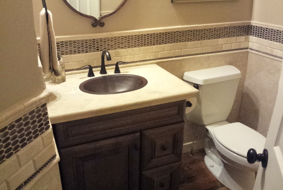 Inspiration for a small contemporary cloakroom in Atlanta with a built-in sink, raised-panel cabinets, dark wood cabinets, a two-piece toilet, beige tiles, stone tiles, beige walls and medium hardwood flooring.