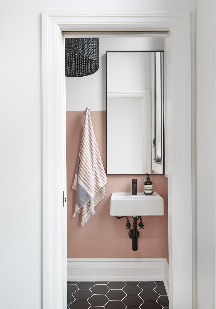 トロントにあるトランジショナルスタイルのおしゃれなトイレ・洗面所 (ピンクの壁、壁付け型シンク、黒い床) の写真
