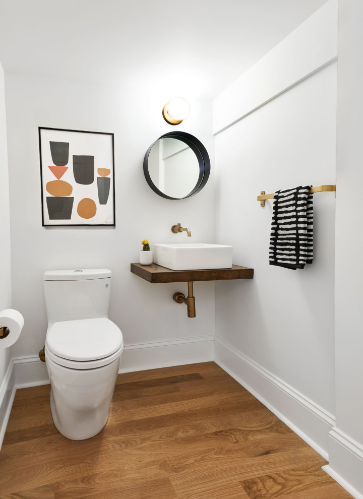 Идея дизайна: туалет в стиле неоклассика (современная классика) с унитазом-моноблоком, белыми стенами, паркетным полом среднего тона, настольной раковиной, столешницей из дерева, коричневым полом и коричневой столешницей