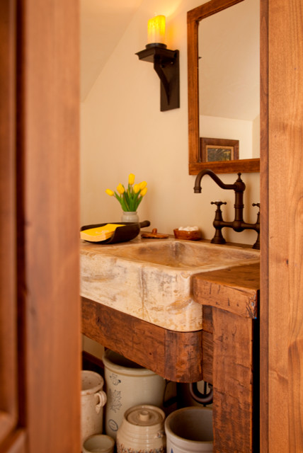 Immagine di un bagno di servizio rustico di medie dimensioni con pareti beige, lavabo da incasso e top in pietra calcarea