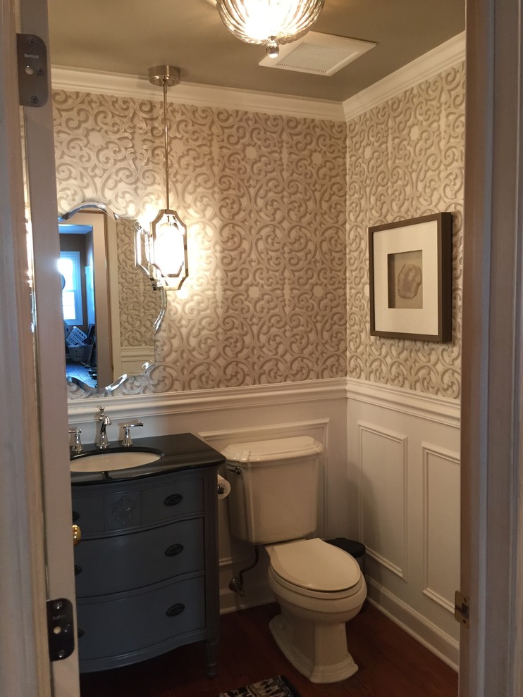 Small traditional cloakroom in Chicago with freestanding cabinets, blue cabinets, a two-piece toilet, white walls, medium hardwood flooring, a submerged sink, marble worktops, brown floors and black worktops.