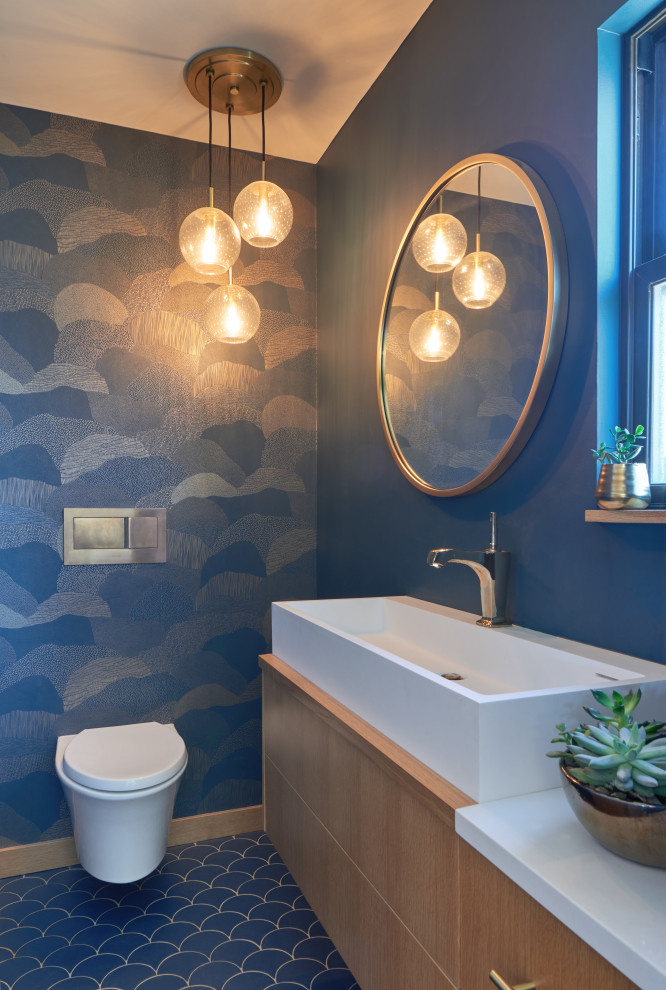 Kleine Moderne Gästetoilette mit flächenbündigen Schrankfronten, hellen Holzschränken, Wandtoilette, blauer Wandfarbe, Keramikboden, Trogwaschbecken, Quarzwerkstein-Waschtisch, blauem Boden und weißer Waschtischplatte in Sonstige