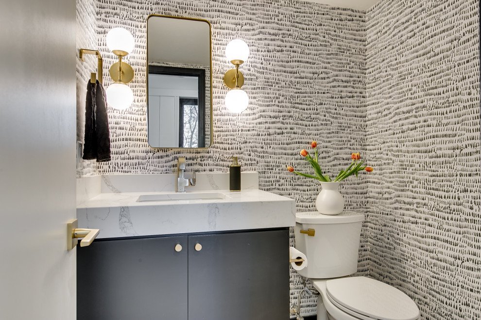 На фото: туалет в современном стиле с плоскими фасадами, серыми фасадами, разноцветными стенами, врезной раковиной, белой столешницей, встроенной тумбой и обоями на стенах