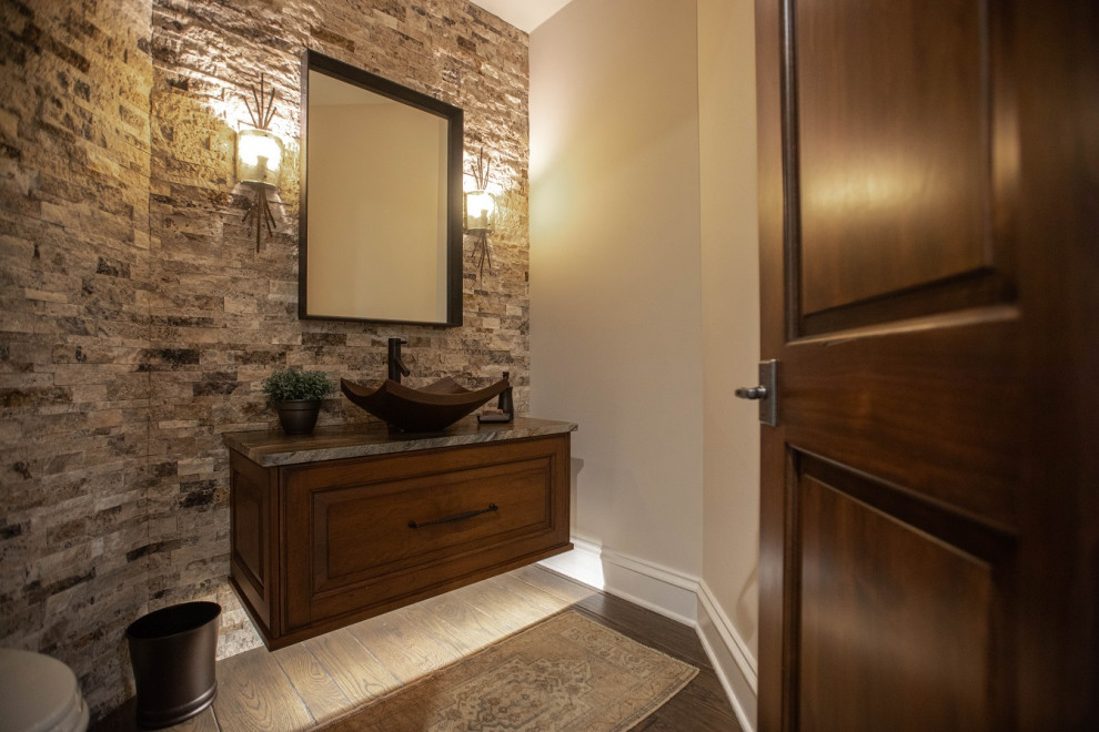Cette image montre un WC et toilettes traditionnel en bois brun de taille moyenne avec un placard avec porte à panneau surélevé, un carrelage multicolore, un carrelage de pierre, un mur beige, une vasque, un plan de toilette en quartz, un sol marron et un plan de toilette marron.