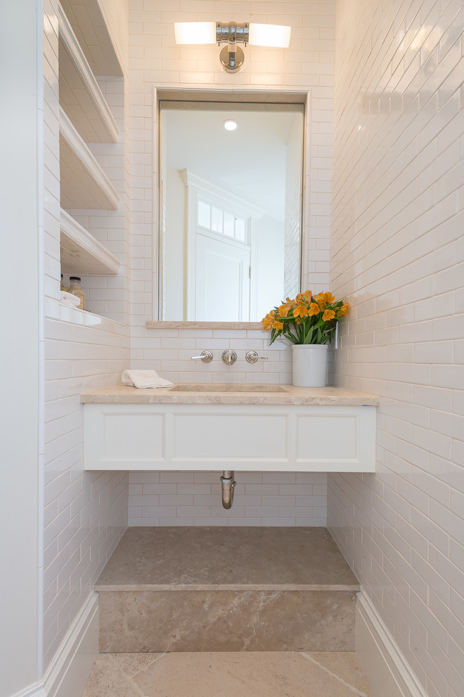 На фото: туалет в морском стиле с врезной раковиной, белой плиткой и полом из известняка с