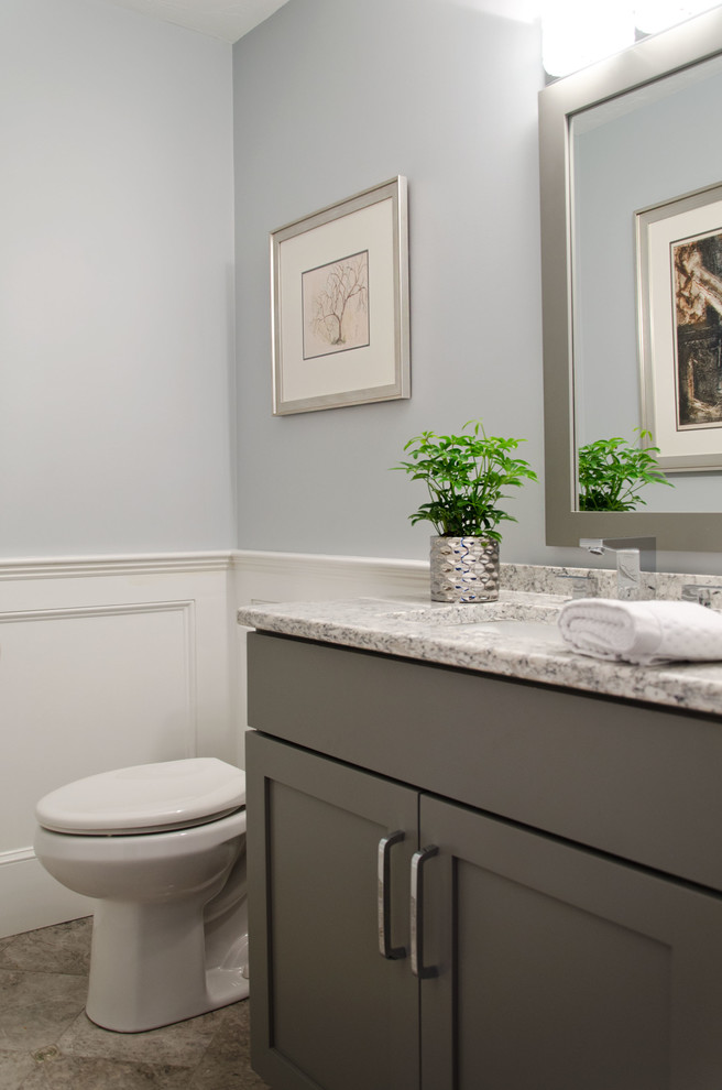 Cette photo montre un petit WC et toilettes chic avec un placard avec porte à panneau encastré, des portes de placard grises, WC à poser, un mur bleu, un sol en calcaire, un lavabo encastré, un plan de toilette en quartz modifié et un sol gris.