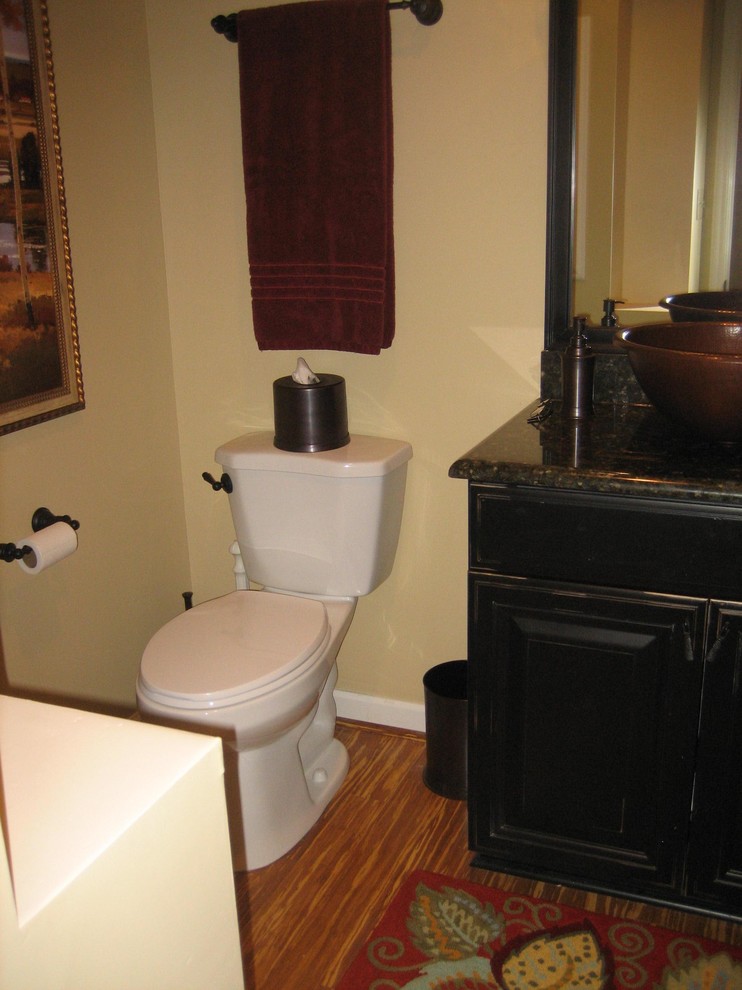 Exempel på ett litet klassiskt svart svart toalett, med luckor med upphöjd panel, svarta skåp, en toalettstol med separat cisternkåpa, beige väggar, mörkt trägolv, ett fristående handfat, granitbänkskiva och brunt golv