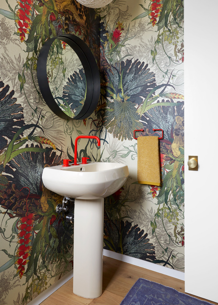 Пример оригинального дизайна: туалет среднего размера в современном стиле с светлым паркетным полом, раковиной с пьедесталом, разноцветными стенами, бежевым полом и обоями на стенах