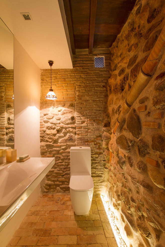 Esempio di un piccolo bagno di servizio stile rurale con WC a due pezzi, pareti beige, lavabo rettangolare e pavimento in mattoni