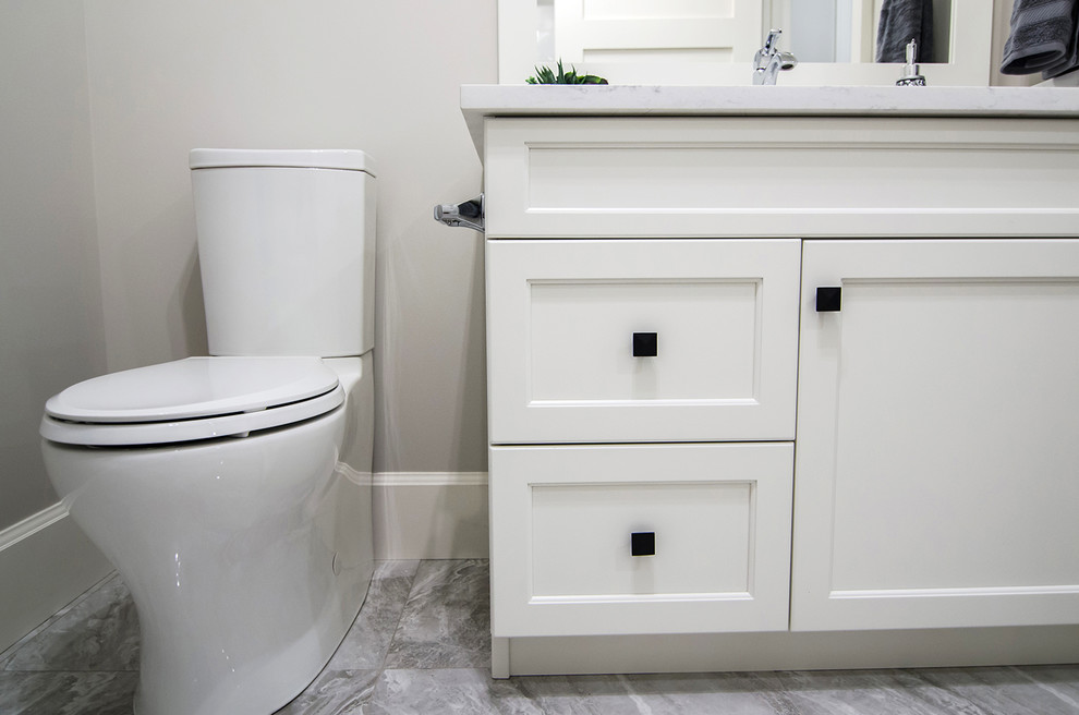 Aménagement d'un petit WC et toilettes contemporain avec un placard avec porte à panneau encastré, des portes de placard blanches, WC séparés, un mur gris, un lavabo encastré, un plan de toilette en marbre, un sol gris et un plan de toilette blanc.