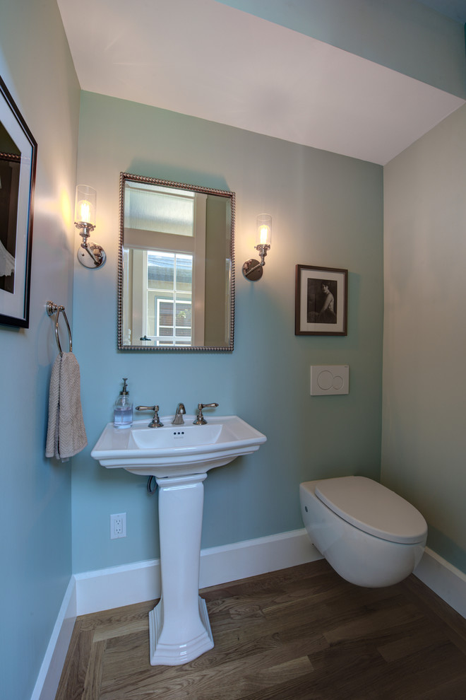 Idéer för mellanstora vintage toaletter, med en vägghängd toalettstol, blå väggar, mellanmörkt trägolv, ett piedestal handfat och brunt golv