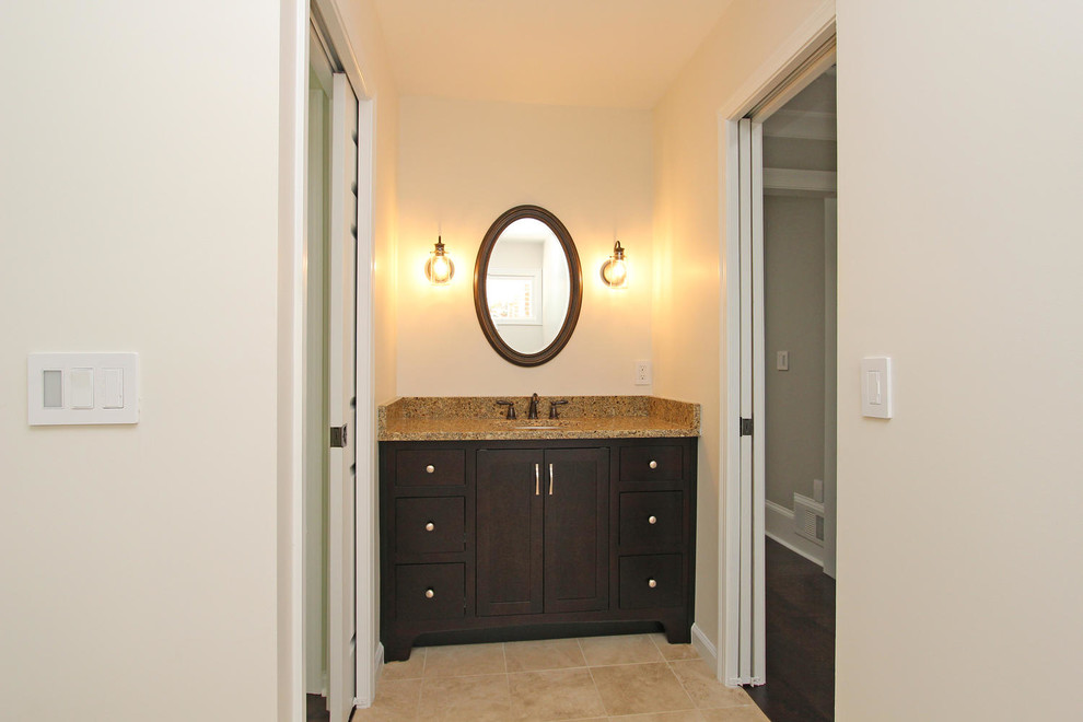 Immagine di un bagno di servizio chic di medie dimensioni con ante in stile shaker, ante in legno bruno, pareti beige, pavimento in travertino, lavabo sottopiano, top in granito, pavimento beige e top marrone