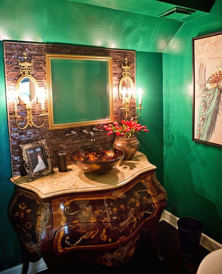 Klassisk inredning av ett litet toalett, med ett fristående handfat, möbel-liknande, marmorbänkskiva, en toalettstol med hel cisternkåpa, brun kakel, gröna väggar, stenkakel och skåp i mörkt trä