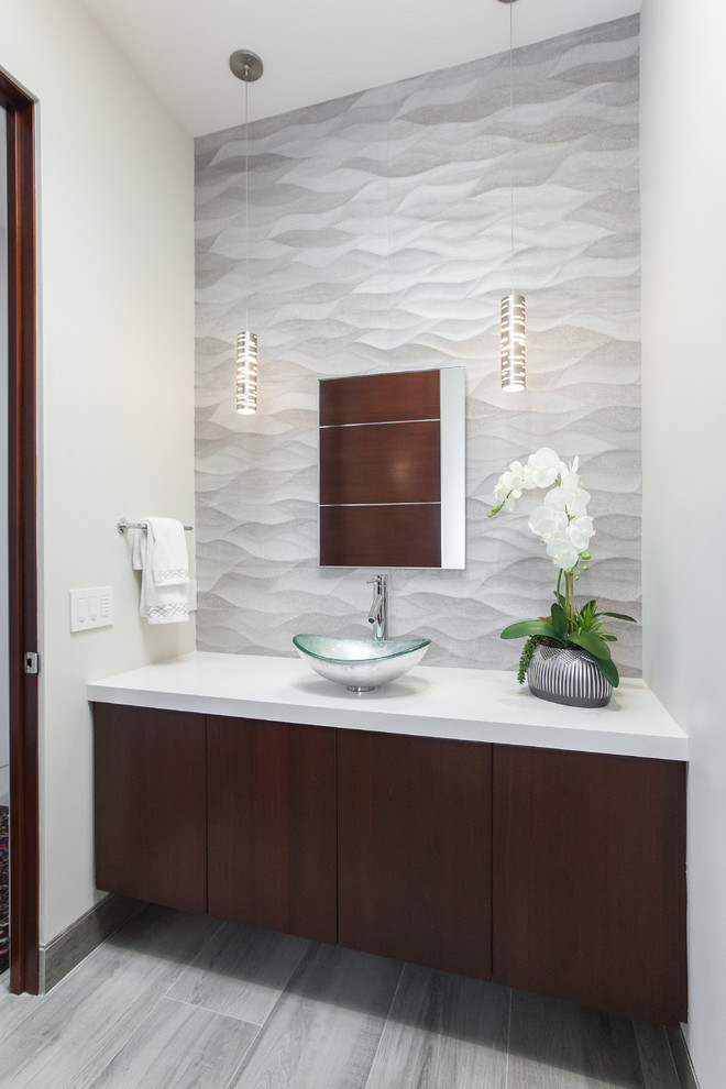 Mittelgroße Moderne Gästetoilette mit flächenbündigen Schrankfronten, dunklen Holzschränken, grauen Fliesen, weißer Wandfarbe, Aufsatzwaschbecken, Quarzwerkstein-Waschtisch und weißer Waschtischplatte in San Diego