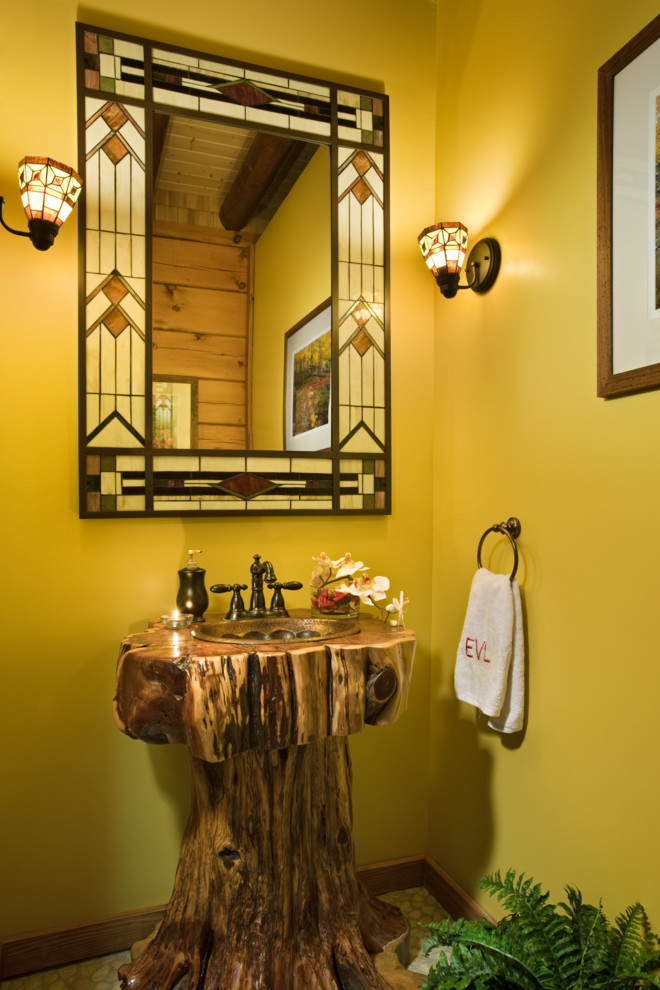 На фото: туалет в стиле рустика с раковиной с пьедесталом, желтыми стенами и полом из галечной плитки с
