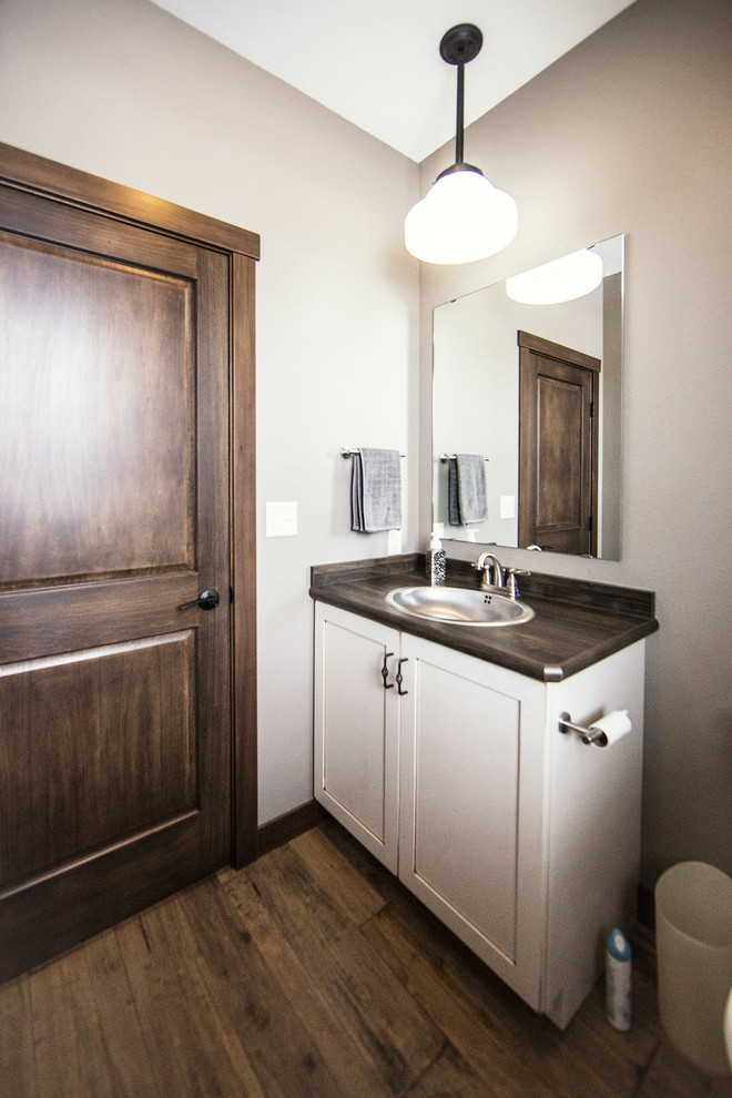 Inspiration for a medium sized classic cloakroom in Other with recessed-panel cabinets, white cabinets, grey walls, dark hardwood flooring, a built-in sink, engineered stone worktops and brown floors.