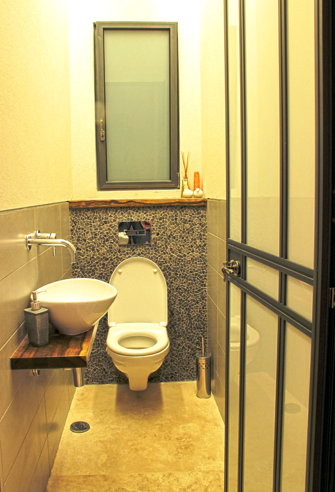 Exempel på ett litet modernt toalett, med en vägghängd toalettstol, svart kakel, mosaik, grå väggar, marmorgolv, ett fristående handfat, träbänkskiva och beiget golv