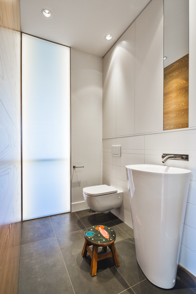 Idée de décoration pour un petit WC suspendu design avec un carrelage blanc, des carreaux de céramique, un mur blanc, un sol en calcaire, un lavabo de ferme et un sol gris.