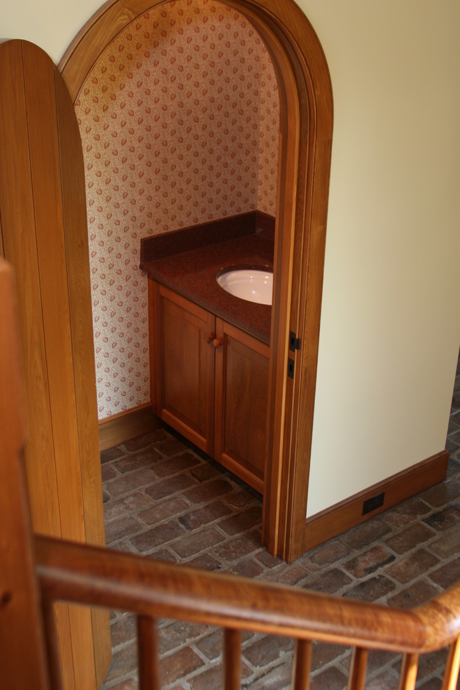 Aménagement d'un petit WC et toilettes montagne en bois brun avec un lavabo encastré, un plan de toilette en quartz modifié et un placard avec porte à panneau encastré.
