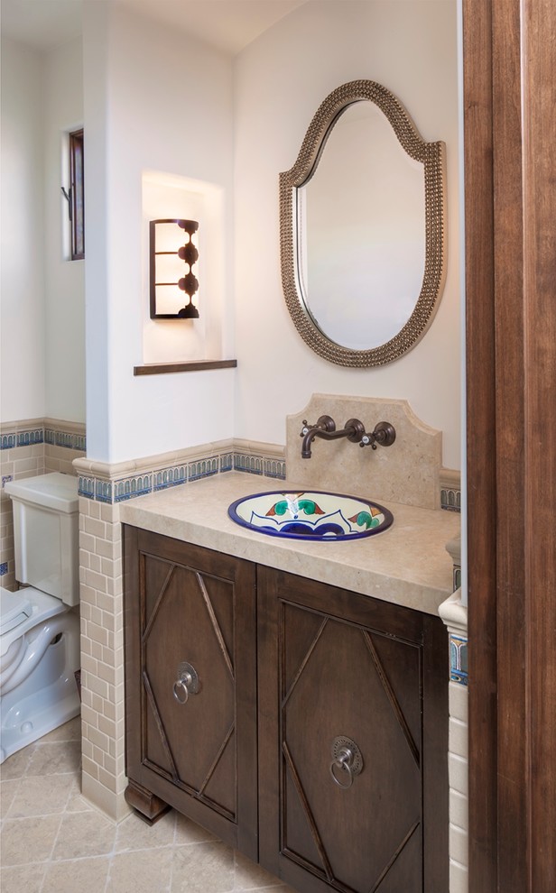 Mediterrane Gästetoilette mit Einbauwaschbecken, dunklen Holzschränken, beigen Fliesen und weißer Wandfarbe in Los Angeles
