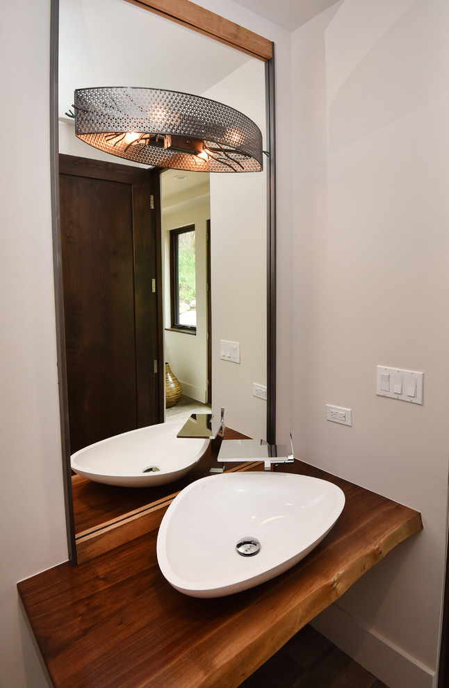 Inredning av ett modernt mellanstort brun brunt toalett, med beige väggar, ett fristående handfat och träbänkskiva