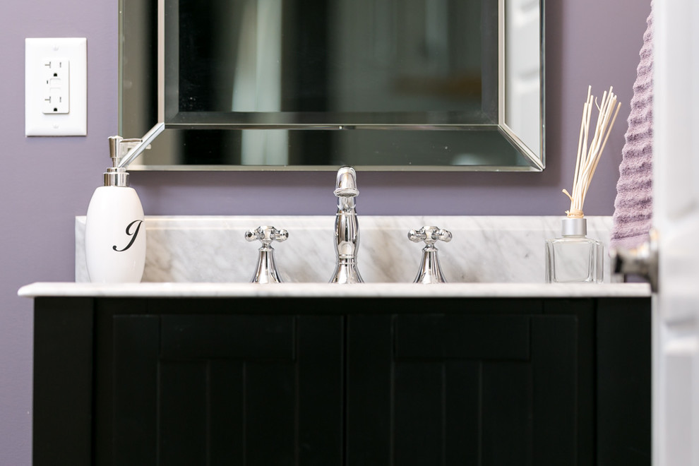 Cette image montre un WC et toilettes craftsman avec un placard à porte persienne, des portes de placard noires, un mur violet, un lavabo encastré et un plan de toilette en marbre.