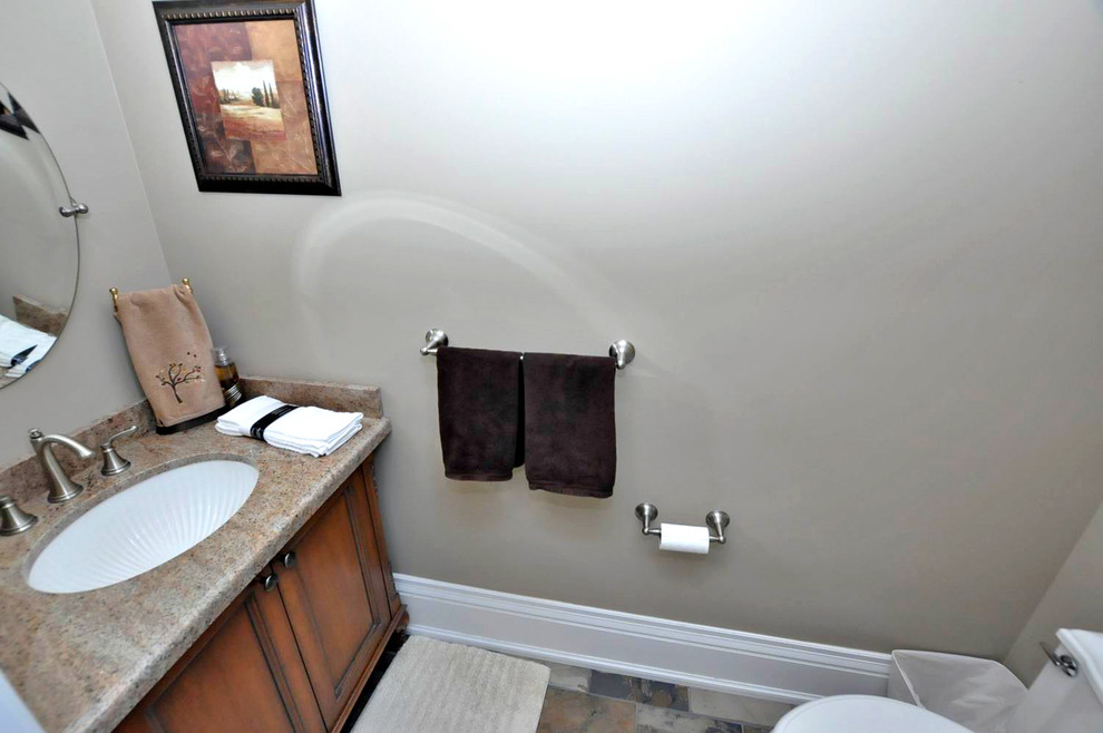 Foto på ett mellanstort vintage toalett, med luckor med profilerade fronter, skåp i mellenmörkt trä, en toalettstol med separat cisternkåpa, beige väggar, skiffergolv, ett undermonterad handfat, granitbänkskiva och grått golv