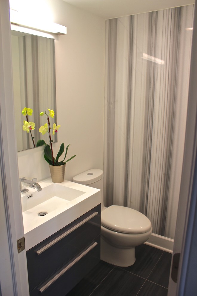 Esempio di un piccolo bagno di servizio moderno con lavabo integrato, ante lisce, ante grigie, top in superficie solida, WC monopezzo, piastrelle grigie e pareti bianche