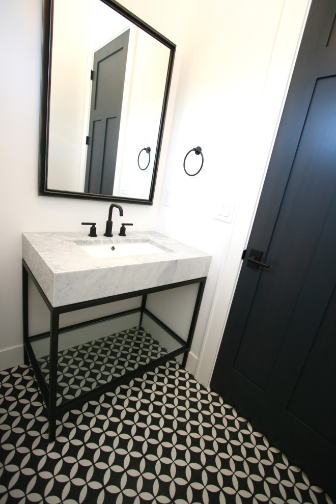 Inredning av ett klassiskt litet grå grått toalett, med möbel-liknande, svarta skåp, en toalettstol med separat cisternkåpa, vita väggar, klinkergolv i terrakotta, ett undermonterad handfat, marmorbänkskiva och svart golv