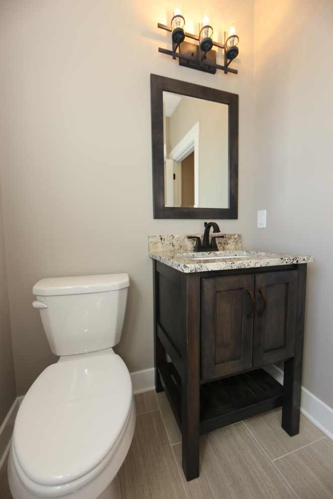 Idée de décoration pour un petit WC et toilettes tradition en bois foncé avec un placard à porte shaker, WC séparés, un mur gris, un sol en vinyl, un lavabo encastré et un plan de toilette en granite.