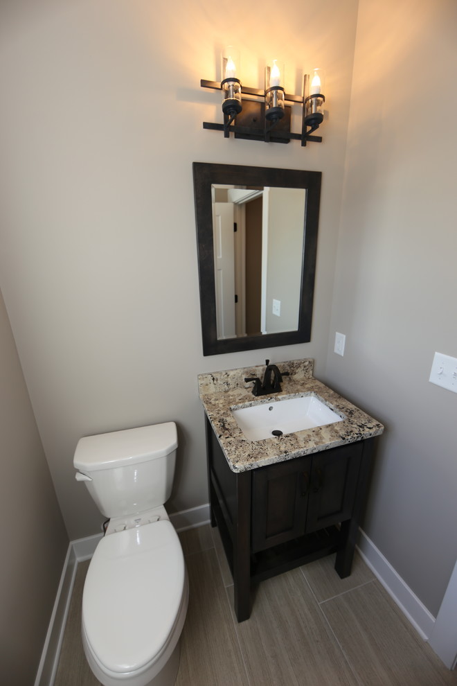 Esempio di un piccolo bagno di servizio tradizionale con ante in stile shaker, ante in legno bruno, WC a due pezzi, pareti grigie, pavimento in vinile, lavabo sottopiano e top in granito