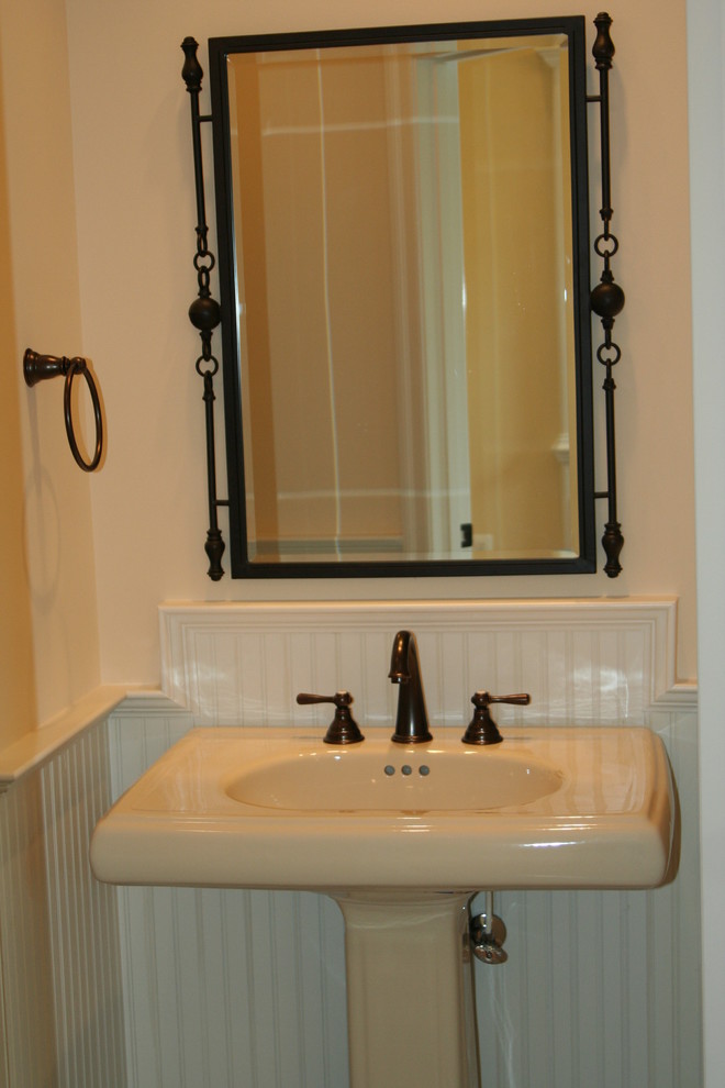 Inredning av ett klassiskt mellanstort toalett, med ett piedestal handfat, en toalettstol med separat cisternkåpa, beige kakel, keramikplattor, vita väggar, klinkergolv i keramik och brunt golv